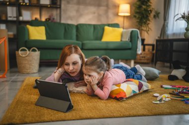 Anne ve kızı evde online video izlemek için dijital tablet kullanıyorlar.