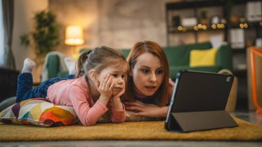 Anne ve kızı evde online video izlemek için dijital tablet kullanıyorlar.