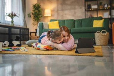 Anne ve kızı evde online video izlemek için dijital tablet kullanıyorlar.