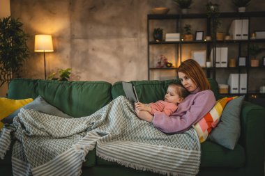 Anne ve kızı evde online video izlemek için dijital tablet kullanıyorlar.