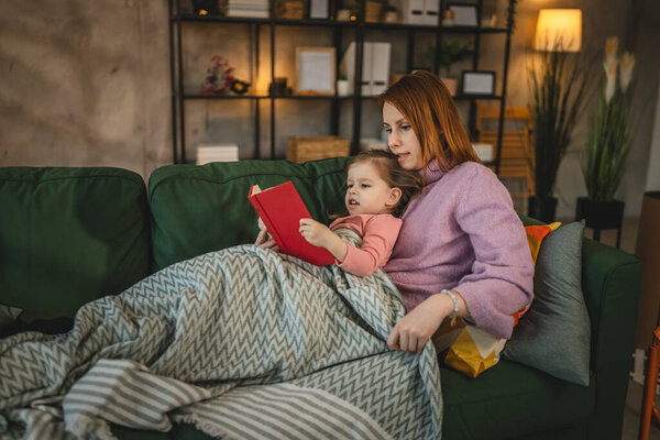 Mother and daughter toddler girl read book at home