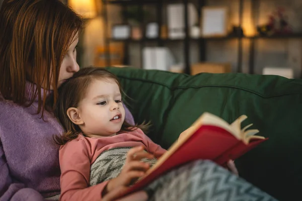 Anne ve kız bebek evde kitap okuyorlar.