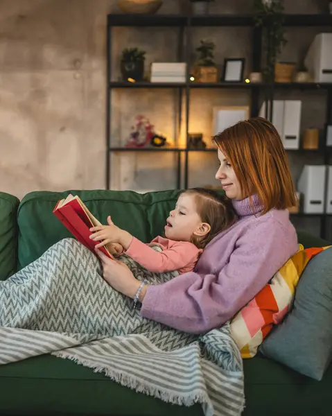Anne ve kız bebek evde kitap okuyorlar.