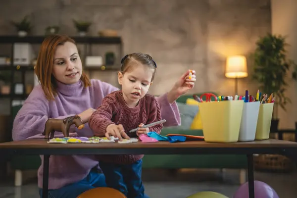 Anne ve kızı yeni yürümeye başlayan çocuk odada el sanatlarında oynuyorlar.