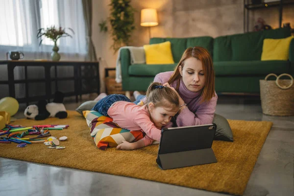 Anne ve kızı evde online video izlemek için dijital tablet kullanıyorlar.