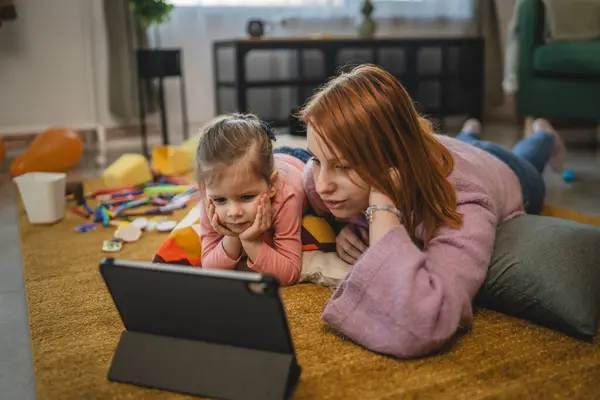 Anne ve kızı evde online video izlemek için dijital tablet kullanıyorlar.