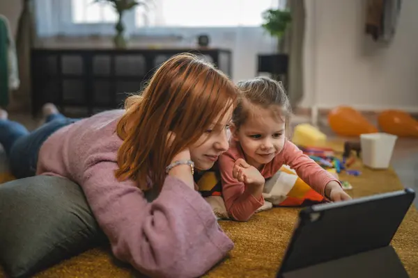 Anne ve kızı evde online video izlemek için dijital tablet kullanıyorlar.