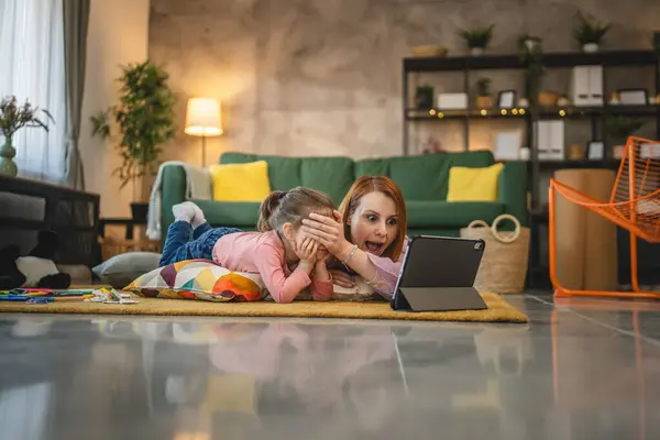 Anne ve kızı evde online video izlemek için dijital tablet kullanıyorlar.