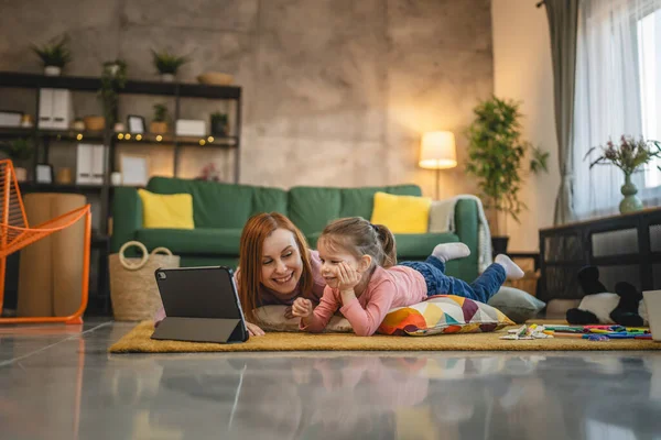 Anne ve kızı evde online video izlemek için dijital tablet kullanıyorlar.