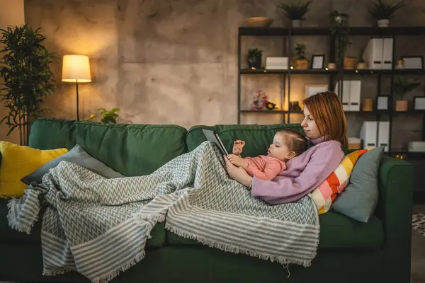 Anne ve kızı evde online video izlemek için dijital tablet kullanıyorlar.