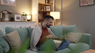 Bir yetişkin erkek beyaz erkek, evdeki film videosunun çekyatında dijital tablet kullanıyor.