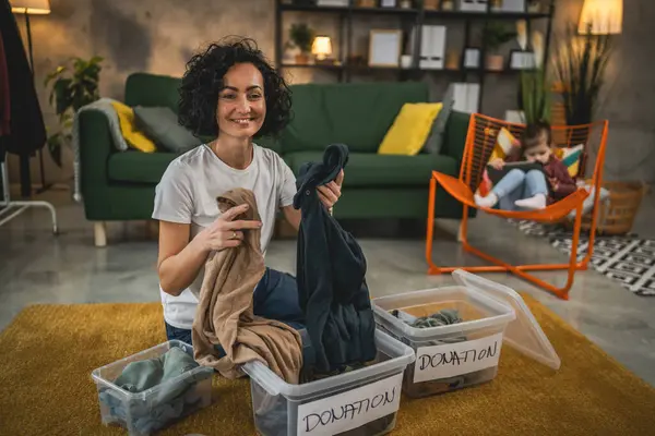Yetişkin Kafkasyalı kadın evde, bağış için kıyafet dolabını düzenliyor.