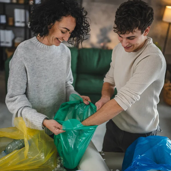 母親と息子の女性と10代の男の家族は 持続可能な生活のコンセプトを袋に廃プラスチック紙とガラスを分類する家庭でリサイクルします — ストック写真