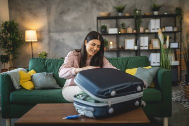 Bir kadın valizini toplayıp tatile hazırlanıyor.