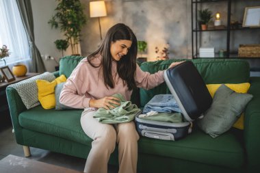 Bir kadın valizini toplayıp tatile hazırlanıyor.