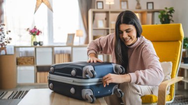 Bir kadın valizini toplayıp tatile hazırlanıyor.