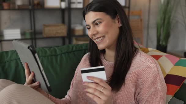 1人の若い成人女性が自宅に座ってクレジットカードをオンラインで買い物 — ストック動画