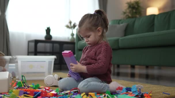 ブロックが付いている家の床で1人の少女の慎重な幼稚園の遊び — ストック動画