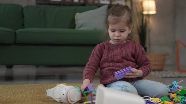 ブロックが付いている家の床で1人の少女の慎重な幼稚園の遊び — ストック動画