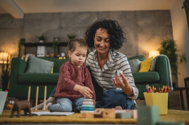 Anne ve kız çocuğu evde oynuyorlar.