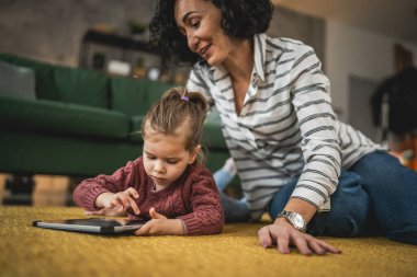 Anne ve kızı evde online video izlemek için dijital tablet kullanıyorlar.