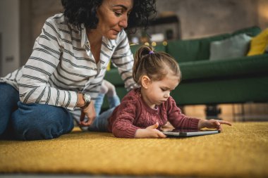 Anne ve kızı evde online video izlemek için dijital tablet kullanıyorlar.