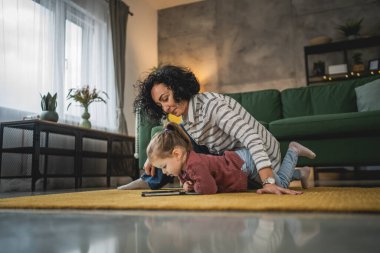 Anne ve kızı evde online video izlemek için dijital tablet kullanıyorlar.