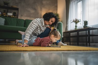 Anne ve kızı evde online video izlemek için dijital tablet kullanıyorlar.