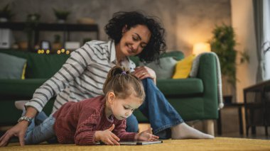 Anne ve kızı evde online video izlemek için dijital tablet kullanıyorlar.