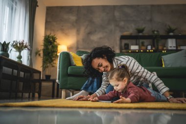 Anne ve kızı evde online video izlemek için dijital tablet kullanıyorlar.