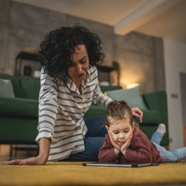 Anne ve kızı evde online video izlemek için dijital tablet kullanıyorlar.