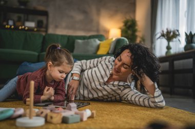 Anne ve kızı evde online video izlemek için dijital tablet kullanıyorlar.