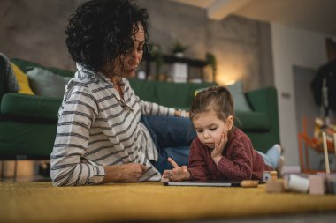 Anne ve kızı evde online video izlemek için dijital tablet kullanıyorlar.