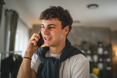 Genç bir adam evde duruyor. Telefon kullan, akıllı telefon kullan.