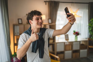 Genç bir adam evde duruyor. Telefon kullan, akıllı telefon kullan.