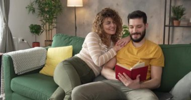 Erkek ve kadın Kafkasyalı yetişkin çift evde kitap okuyor.