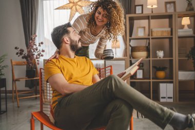 Erkek ve kadın Kafkasyalı yetişkin çift evde kitap okuyor.