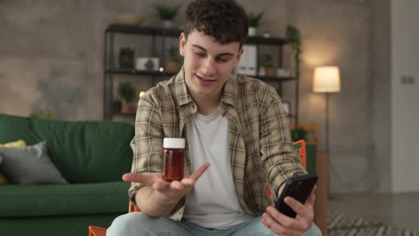 1人の男性が薬の薬の瓶の丸薬を携帯電話の読まれたラベル握ります — ストック動画