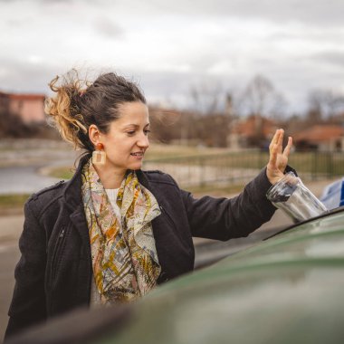 Bir yetişkin kadın cam atık ve yeşil poşetlerle geri dönüşüm kaplarının önünde duruyor ve sıfır atık eko kavramını yeniden kullanmak için şişe kavanozu fırlatıyor.