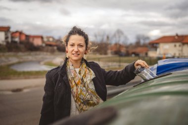 Bir yetişkin kadın cam atık ve yeşil poşetlerle geri dönüşüm kaplarının önünde duruyor ve sıfır atık eko kavramını yeniden kullanmak için şişe kavanozu fırlatıyor.