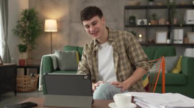 Kafkasyalı genç adam evde oturur dijital tablet kullanır. Belge ya da burs belgesi gösterir. Sınav sonuçları evde mutlu bir gülüş videosu çeker.