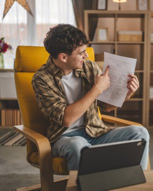 Kafkasyalı genç adam evde oturur dijital tablet kullanır. Belge ya da burs belgesi gösterir. Sınav sonuçları evde mutlu bir gülüş videosu çeker.