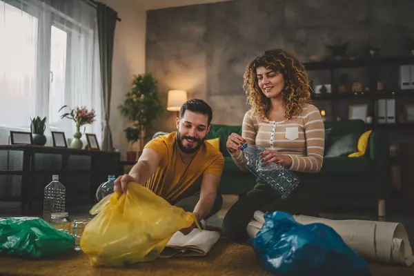 夫と妻の女性と男性の家族は 家庭で廃プラスチック紙とガラスを緑 黄色と青のバッグ持続可能な生活コンセプトに分類するリサイクルします — ストック写真