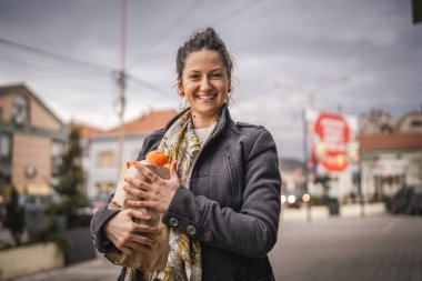Bir kadının portresi organik meyve ve sebzeleri kesekağıdında tutuyor.