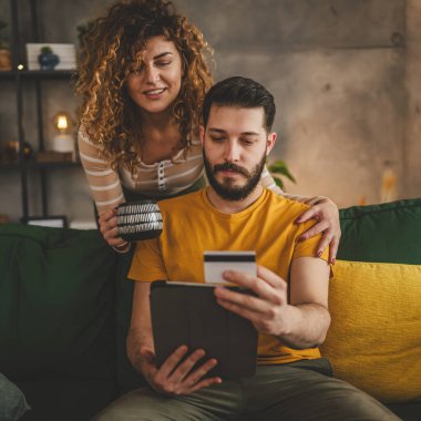 Kafkas erkek ve kadın karı koca ya da sevgili dijital tablet ve kredi kartı alışverişi kullanıyor. İnternetten bir şeyler satın alıyor ya da ödemeyi ev halkının e-ticaretinden yapıyor.