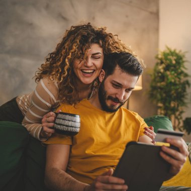 Kafkas erkek ve kadın karı koca ya da sevgili dijital tablet ve kredi kartı alışverişi kullanıyor. İnternetten bir şeyler satın alıyor ya da ödemeyi ev halkının e-ticaretinden yapıyor.