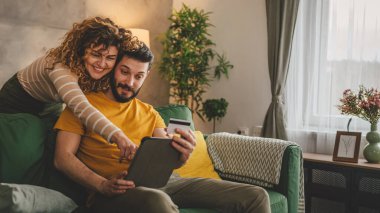 Kafkas erkek ve kadın karı koca ya da sevgili dijital tablet ve kredi kartı alışverişi kullanıyor. İnternetten bir şeyler satın alıyor ya da ödemeyi ev halkının e-ticaretinden yapıyor.