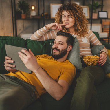 Birkaç beyaz erkek ve kadın evlerinde kanepede film izliyorlar.