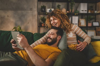 Birkaç beyaz erkek ve kadın evlerinde kanepede film izliyorlar.