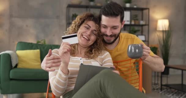カップル慎重な男と女性の夫と妻またはボーイフレンドやガールフレンドは デジタルタブレットやクレジットカードのショッピングをオンラインで購入するか 家の人々から支払い予約電子商取引を行う — ストック動画